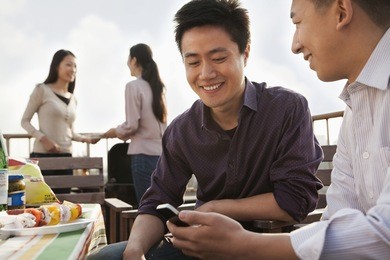 friends using cell phone at rooftop barbecue