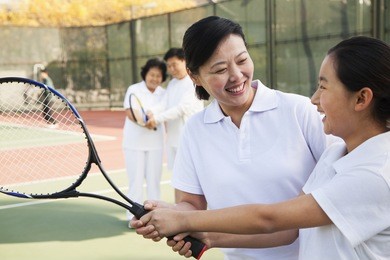young girl playing tennis with her coach