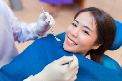 closeup smile of woman having dental teeth examined dentist check-up via excavator in clinic her patient 