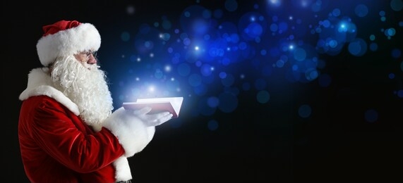 santa claus with magic book on dark background