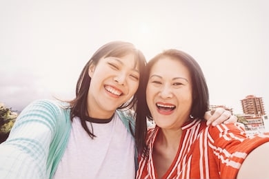happy mother and daughter taking selfie with mobile smartphone outdoor - asian family sharing time and photo together - perenthood, love and people lifestyle concept