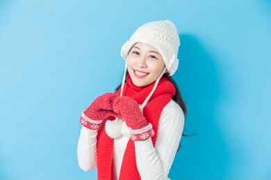 asian woman wear winter clothes and smile isolated on blue background