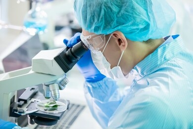 asian male scientist  use microscope to observe green plant in the laboratory