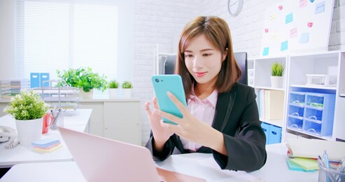 asian business woman use smart phone and feel happy in the office
