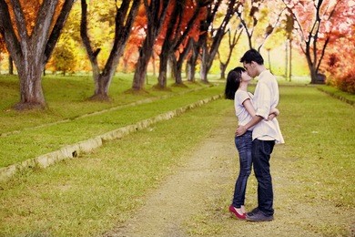 portrait of romantic young couple kissing on the road in autumn day