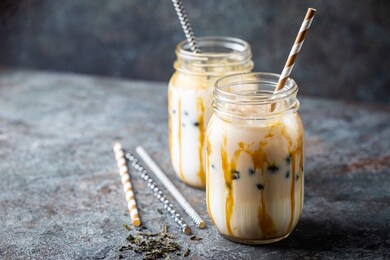 light brown creamy bubble tea with milk and black tapioca in a glass jar on gray background