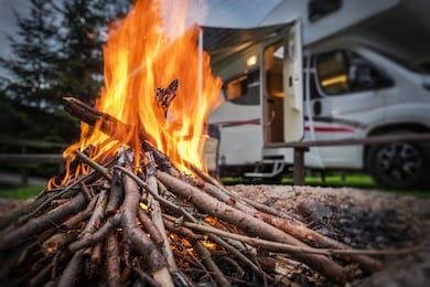 rv park campfire in front of motorhome pitch. summer camping with motorhome.