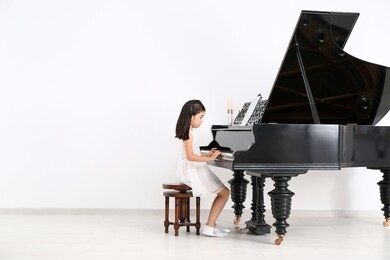 little girl playing grand piano at home