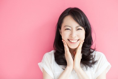 happy young woman against pink background 
