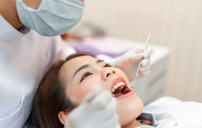 closeup woman having dental teeth examined dentist check-up via excavator in clinic her patient for beautiful smile