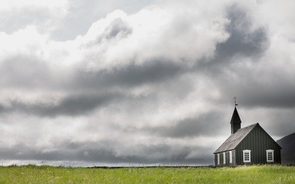 black wooden church against stormy clouds in budir, iceland