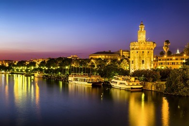 view of golden tower (torre del oro) of seville, andalusia, spain over river guadalquivir at sunset