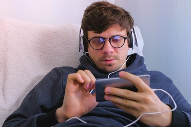 man in glasses and earphones online browsing on smartphone. face close-up