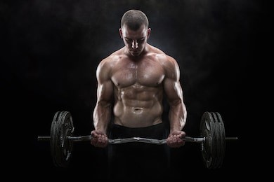 close up of young muscular man lifting weights over dark background