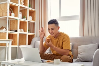 happy young man sitting in sofa and using laptop