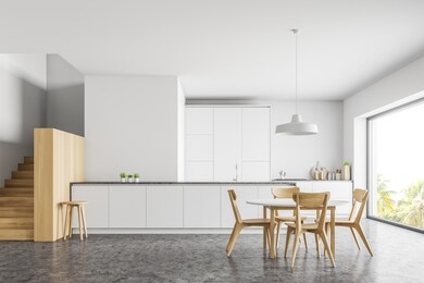 interior of modern kitchen with white walls, concrete floor, wooden stairs, white countertop and bar and round dining table with chairs. 3d rendering