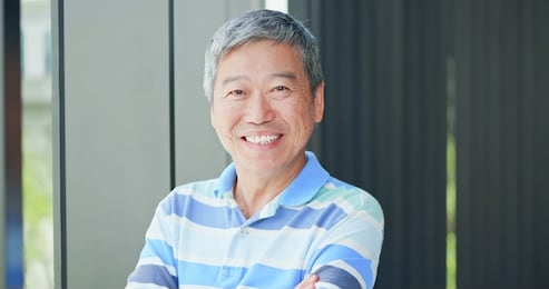 asian elder man look to you with crossed hand and smile
