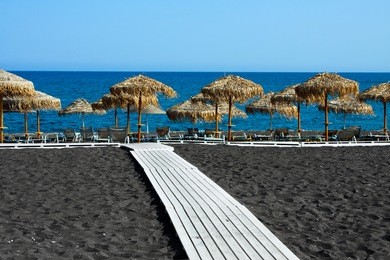seascape and chaise lounges black beach of santorini island, greece