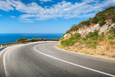 turn of mountain asphalt road with blue sky and sea on a background