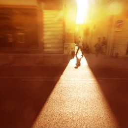 man walking along the street at sunset light.