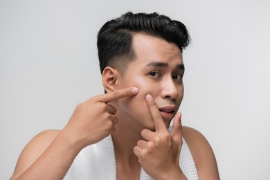 close up photo of young man looking for acnes on his face