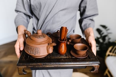 a man holds a tray with a set for a chinese tea ceremony