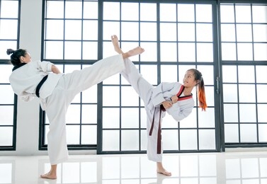 young teacher of taekwondo and her student is acting of kick posture with white background and pattern.