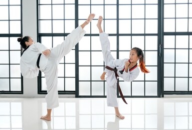 young teacher of taekwondo and her student show action of kick posture together with white background and pattern. this activity is one sport that good for children to exercise and get healthy.