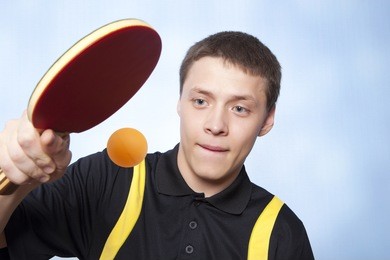 young man playing ping pong against a blue background 