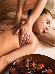 portrait of beautiful young woman relaxing with back massage at spa salon.