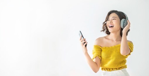 portrait of young beautiful asian woman relax listen to music sing and dance from headphone in bedroom. smile happy asian girl with smartphone, technology connection network, lifestyle concept banner
