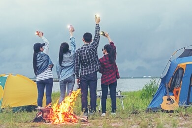 party camping.  group asian family and friends travel enjoy party and roasted sausages relax in vacations. campfire at touristic camp at nature in outdoor forest.  travel concept
