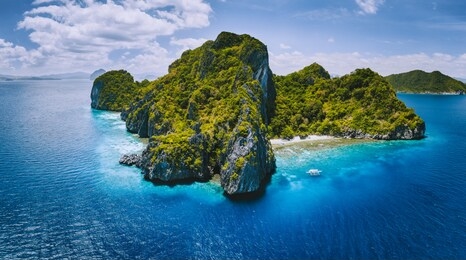 aerial drone panorama view of tropical paradise island. karst limestone rocky mountains surrounds by blue ocean and coral reef