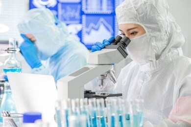 asian biotechnology research team look microscope with cleanroom clothes and conduct experiments in the laboratory