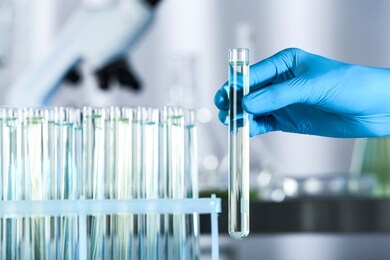 doctor holding test tube with sample for analysis in laboratory, closeup