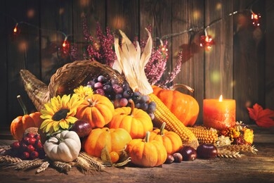 happy thanksgiving. decorative cornucopia with pumpkins, squash, fruits and falling leaves on rustic wooden table
