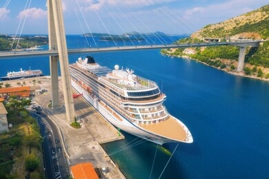 aerial view of cruise ship and beautiful bridge in dubrovnik, croatia. top view of large ship and road at sunset. summer landscape with harbor, mountain, blue sea and green trees. cruise liner in port