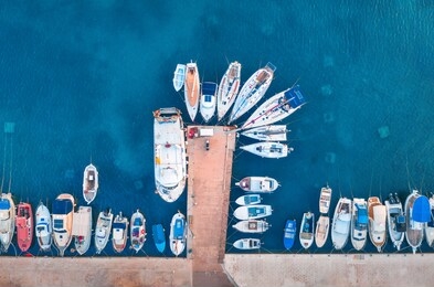 aerial view of the boats and yachts on tropical sea coast at sunset in summer. colorful landscape with pier, boat, ocean with transparent blue water. top view of motorboats in harbor. travel