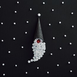 christmas minimal concept - santa claus creative minimal on black background. santa claus hat made of black ice cream cone and snowball. stylish christmas creative minimal idea. snowfall pattern