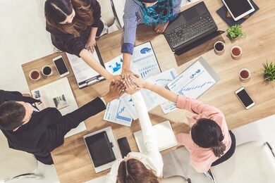 businessmen and businesswomen joining hands in group meeting at multicultural office room showing teamwork, support and unity in business. diversity workplace and corporate people working concept.