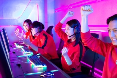 team of asian teenage cyber sport gamers win the multiplayer pc video game on esport tournament and cheer with hand up