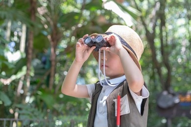 a little boy with binoculars during hiking in the forest. the child is looking through binoculars. concept of kid's adventure.