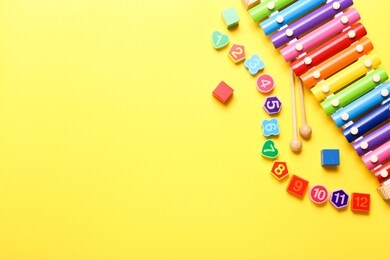 colorful kids toys on yellow background. top view, flat lay.