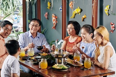 happy big asian family talking, laughing and eating good food at dinner