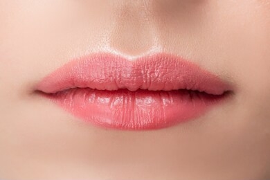 beautiful natural female lips close-up with pink permanent makeup stick.