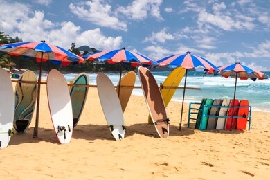 surfboards and bodyboards under umbrellas on surin beach, phuket, thailand