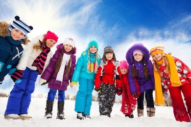 large group of kids, boys and girls 5-10 years old bending down, holding hands, standing together in a row