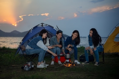 asian teenagers camping by the lake in sunset. 