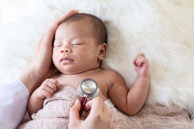 asian newborn baby get sick crying during examine by pediatrician doctor hand hold stethoscope, doctor monitoring heart pulse rate adorable newborn crying on bed in clinic, baby health care concept 