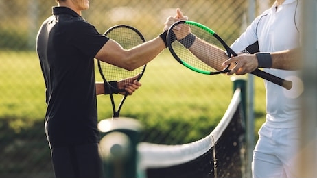 two young man shaking hands after playing tennis. tennis players shaking hands over the net after the match.